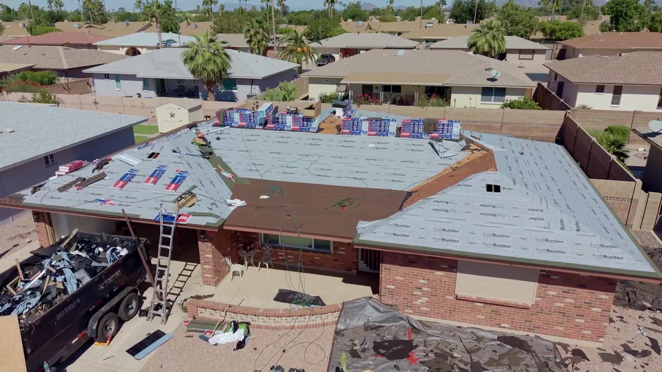 The same roof covered in new underlayment, with shingle bundles staged on the ridge